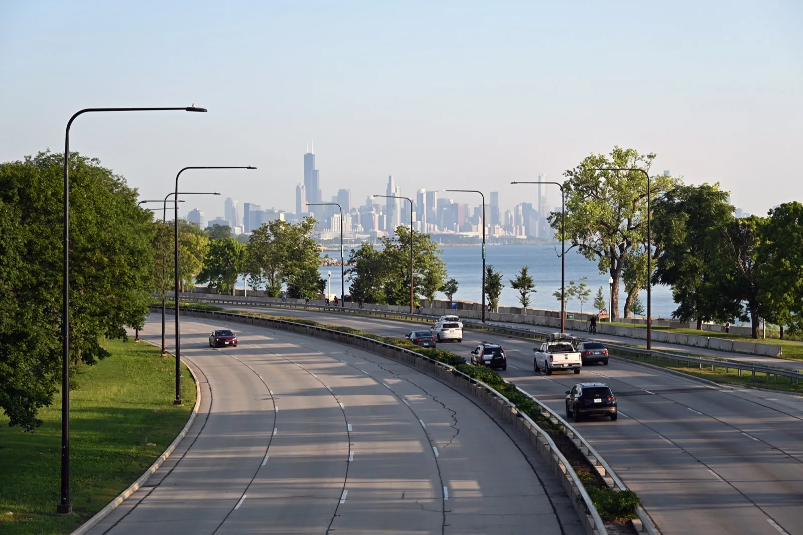 Lake Shore Drive in Chicago on a summer morning, with light traffic, trees along Lake Michigan, and the downtown skyline in the distance