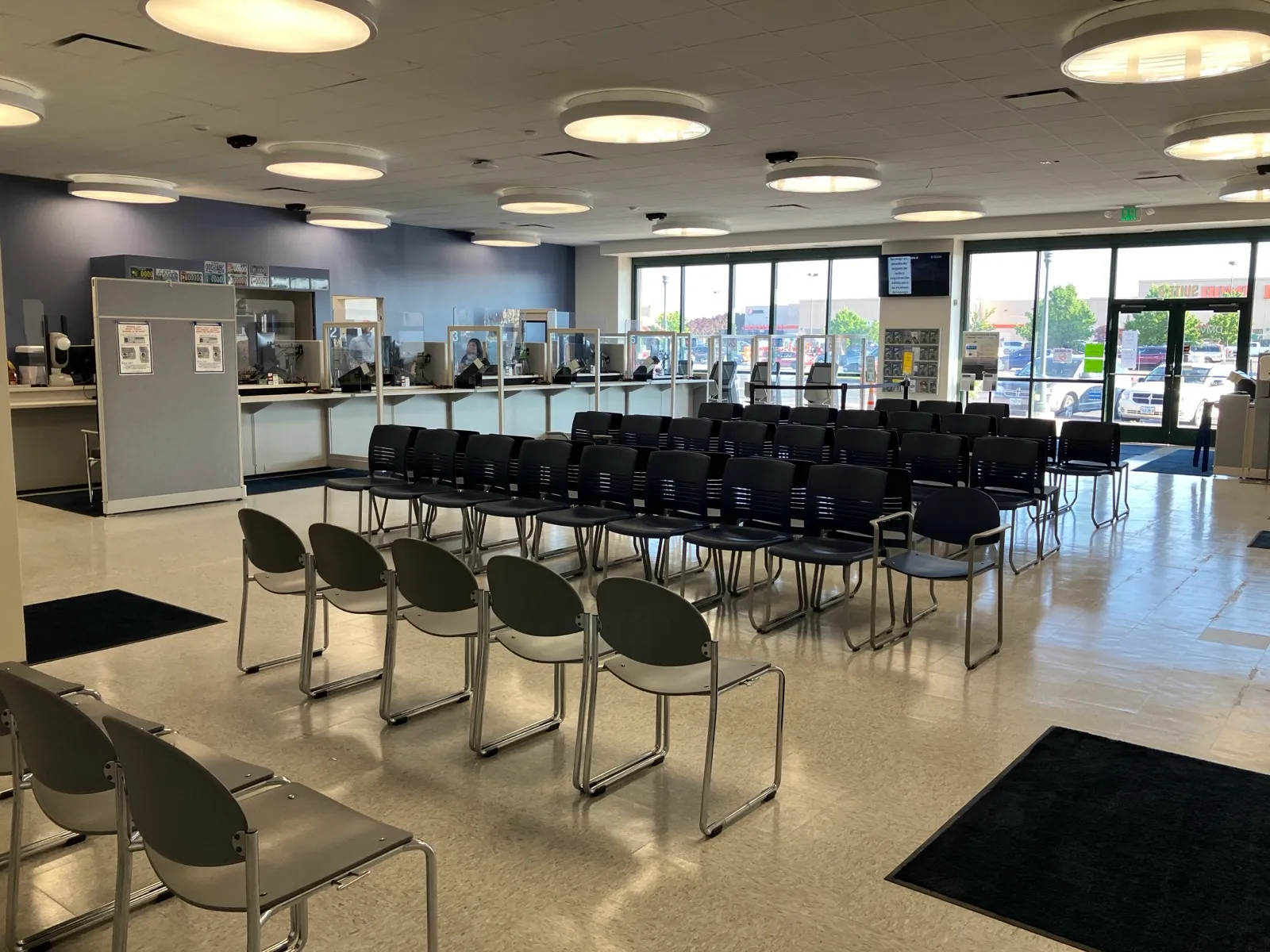 The inside of a state driver licensing office, with rows of empty chairs facing a long counter of service windows