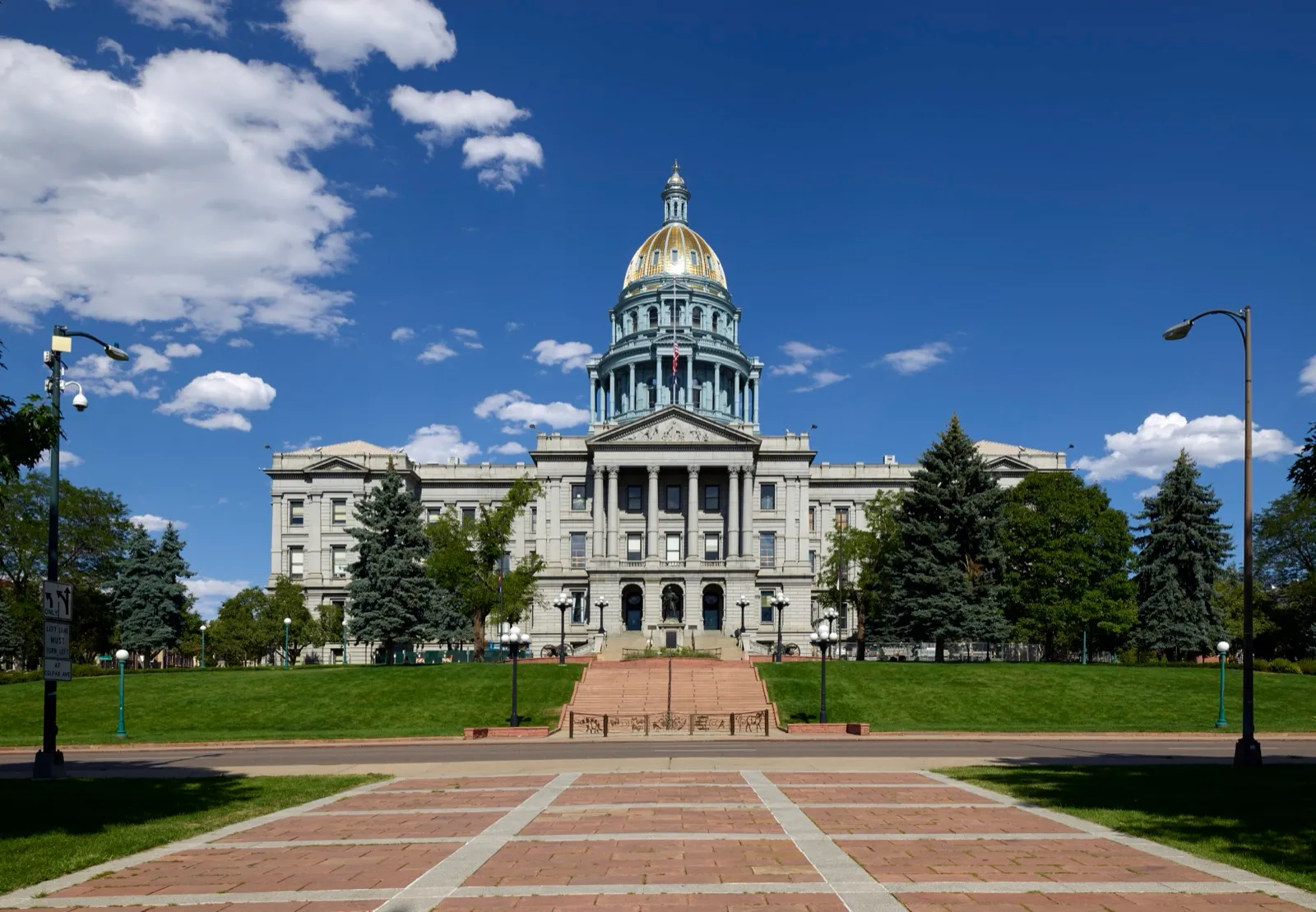 The Colorado State Capitol in Denver, with its gold dome, under a blue sky with scattered clouds