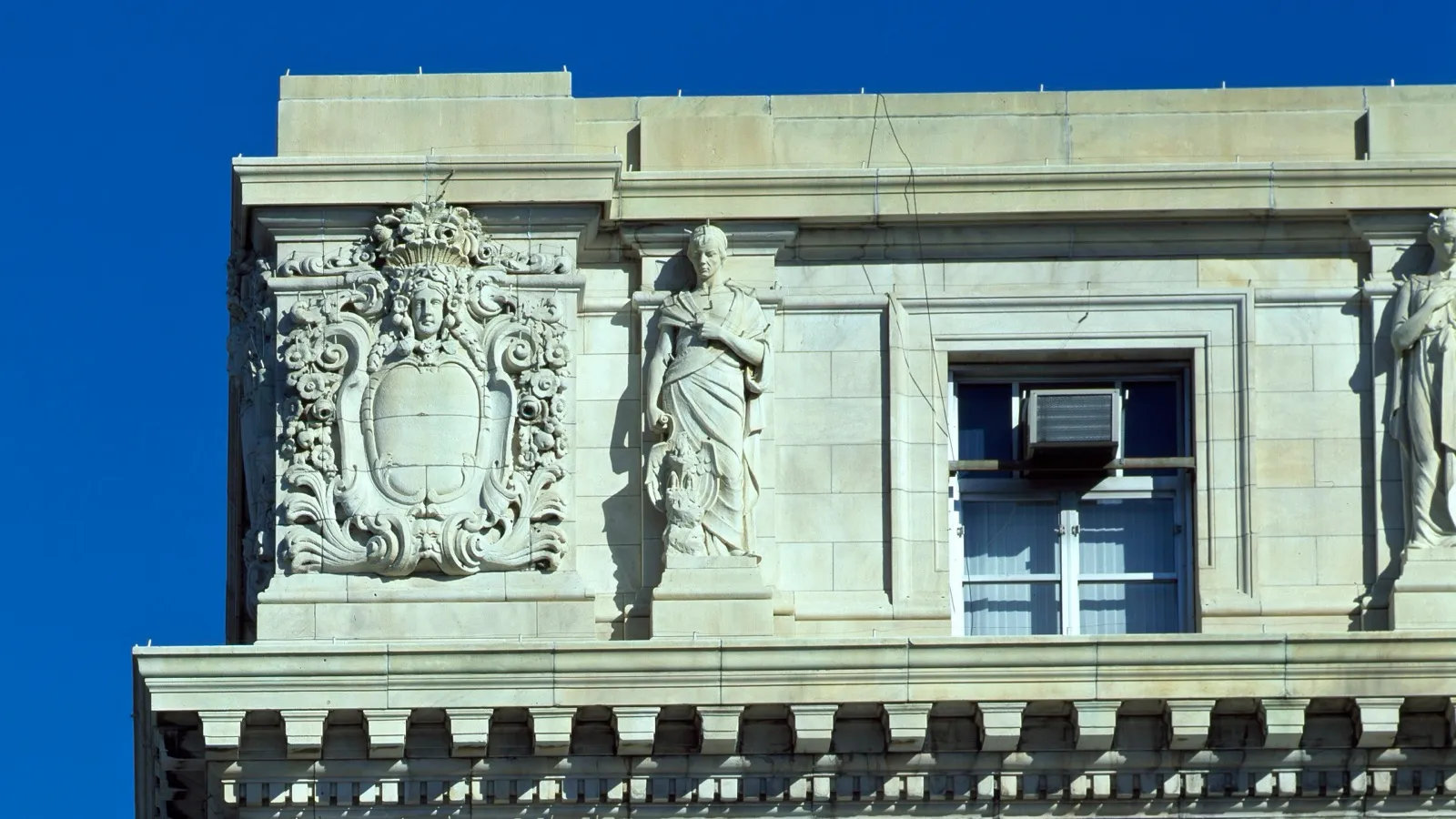 A carved stone crest and a statue on the top floor of the John A. Wilson Building, the DC government building where the Council meets
