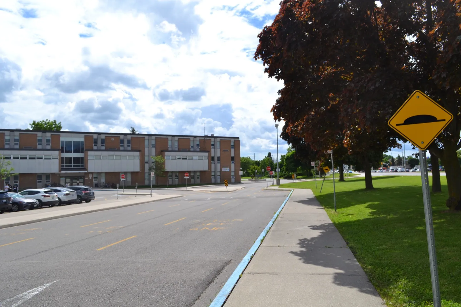 An empty school drop-off lane in front of a brick school building on a sunny day