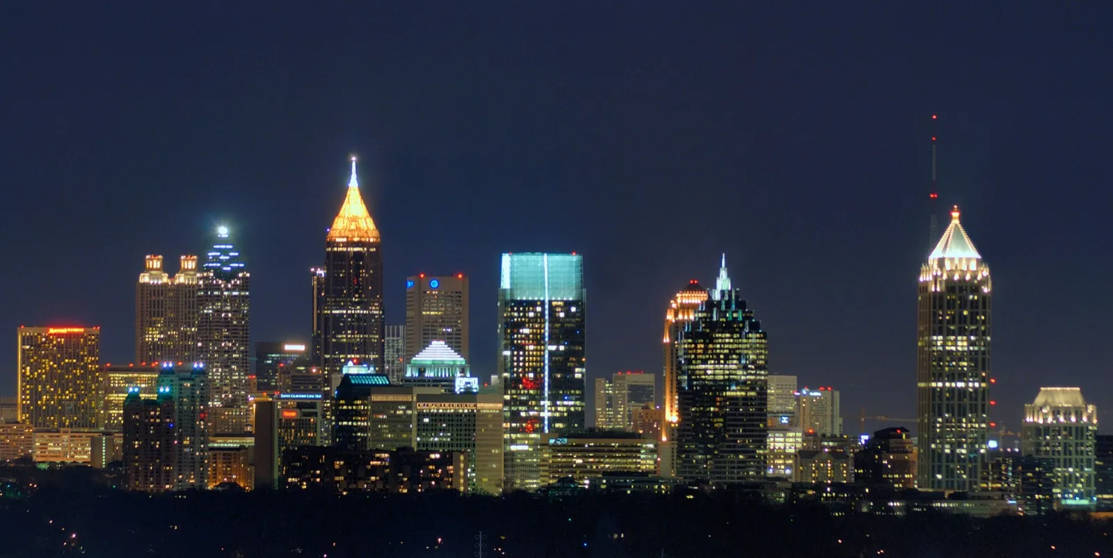 The Atlanta skyline lit up at night, with the towers of downtown and Midtown against a dark blue sky