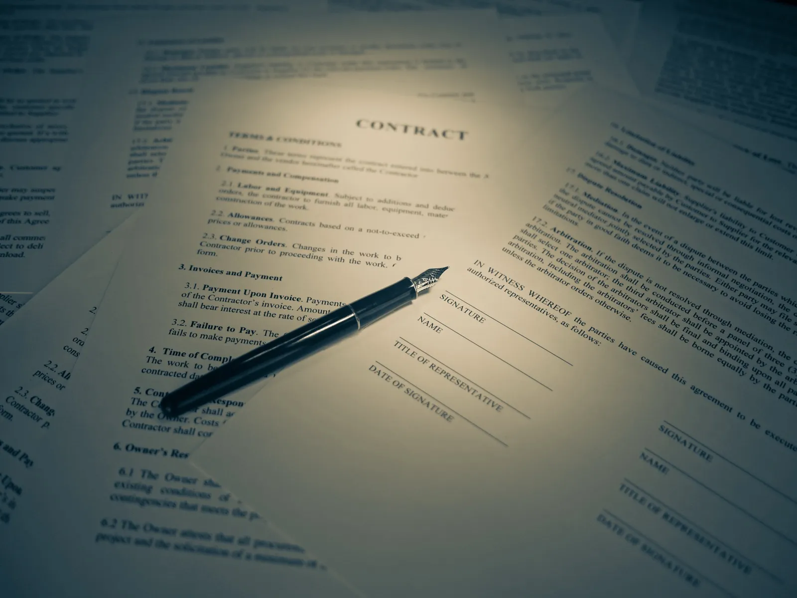 A printed contract with signature lines and a fountain pen lying on top of other papers