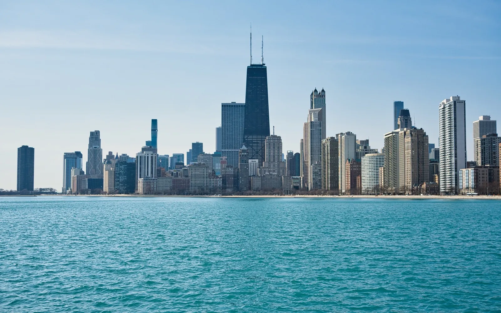 The Chicago skyline across the blue water of Lake Michigan, seen from the North Avenue Beach pier on a clear morning