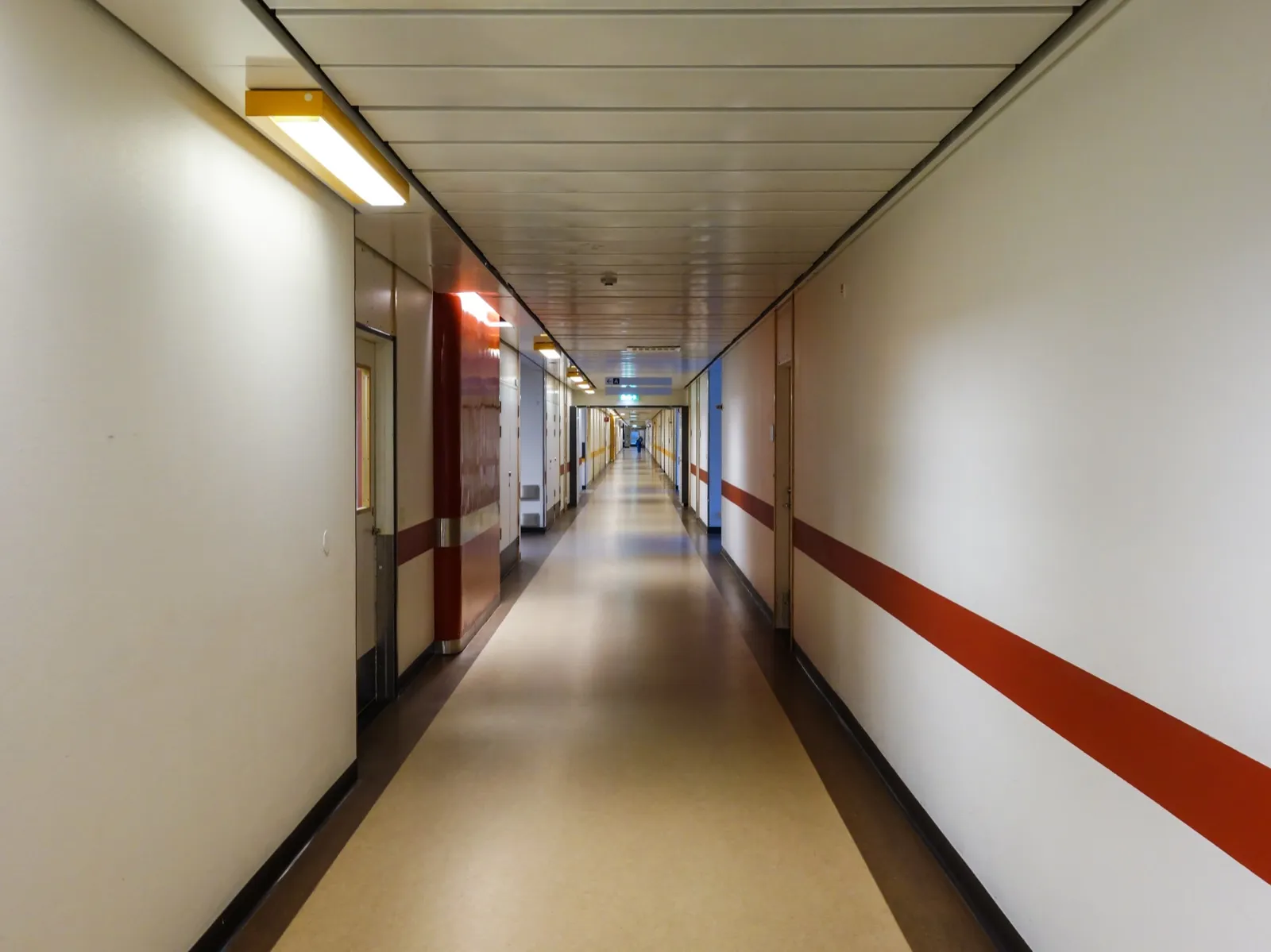 A long, quiet hospital corridor with doors along both walls