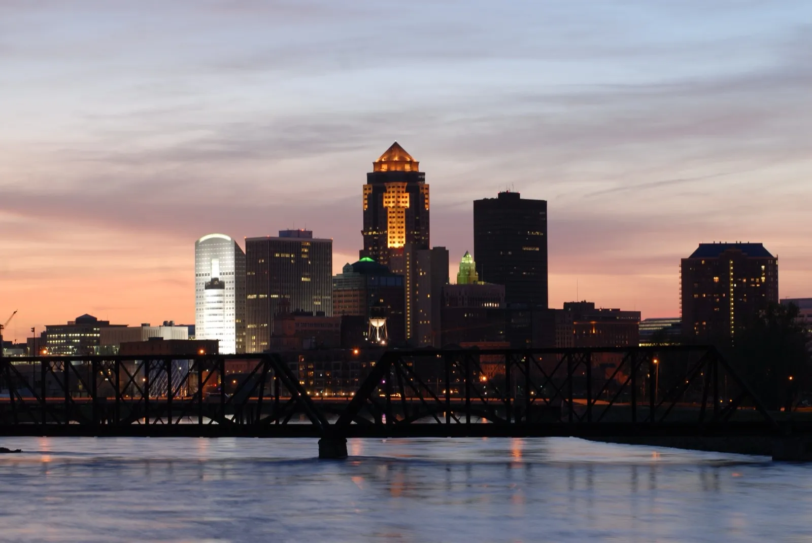 The Des Moines skyline at sundown, with a steel truss bridge over the Des Moines River in front