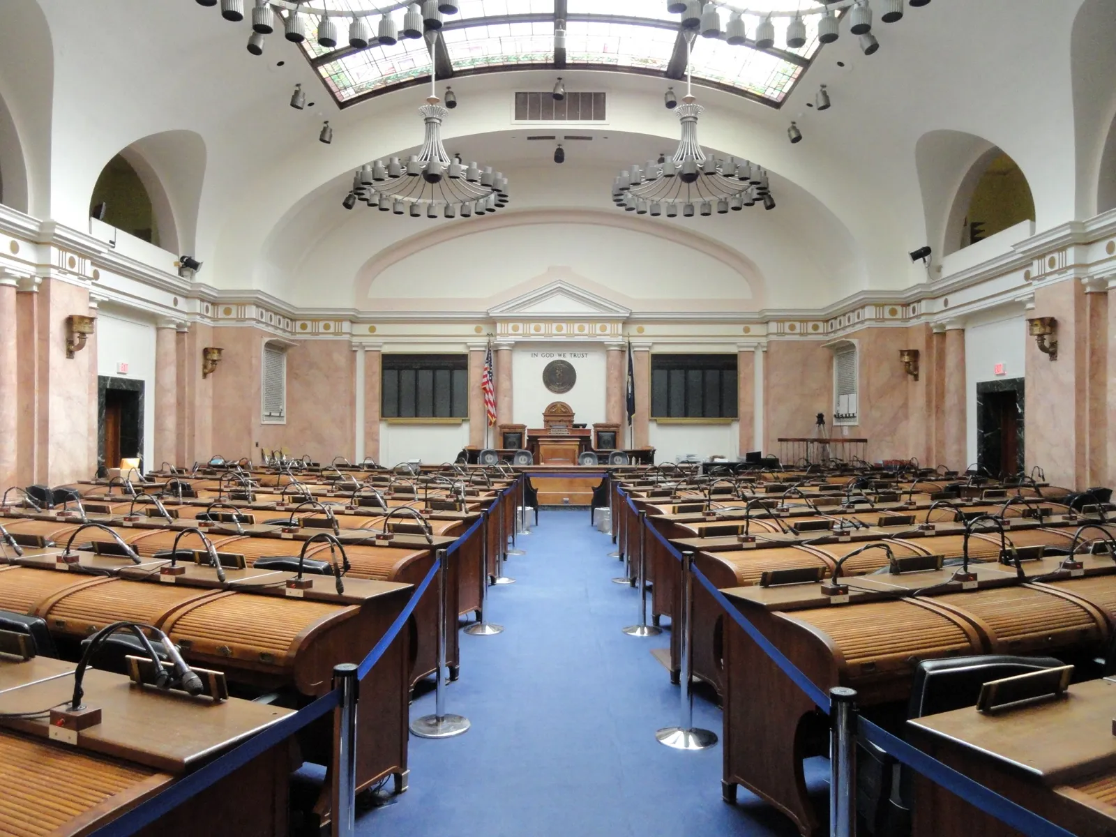 The empty House of Representatives chamber in the Kentucky State Capitol, with rows of wooden desks facing the speaker's rostrum