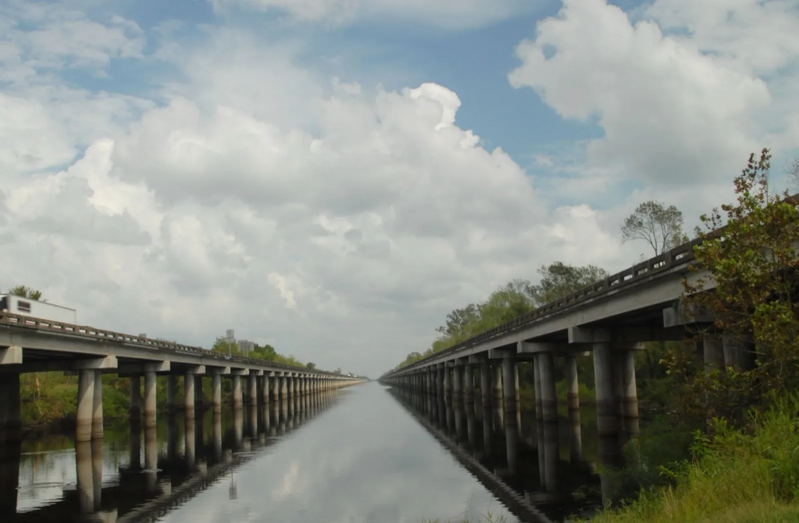 Interstate 10 crossing the Atchafalaya Basin at Whiskey Bay on two long, low bridges over calm water under a cloudy sky