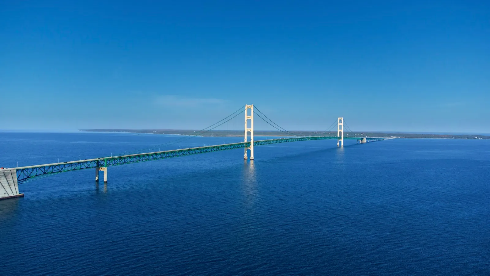 The Mackinac Bridge stretching across the blue water of the Straits of Mackinac on a clear day