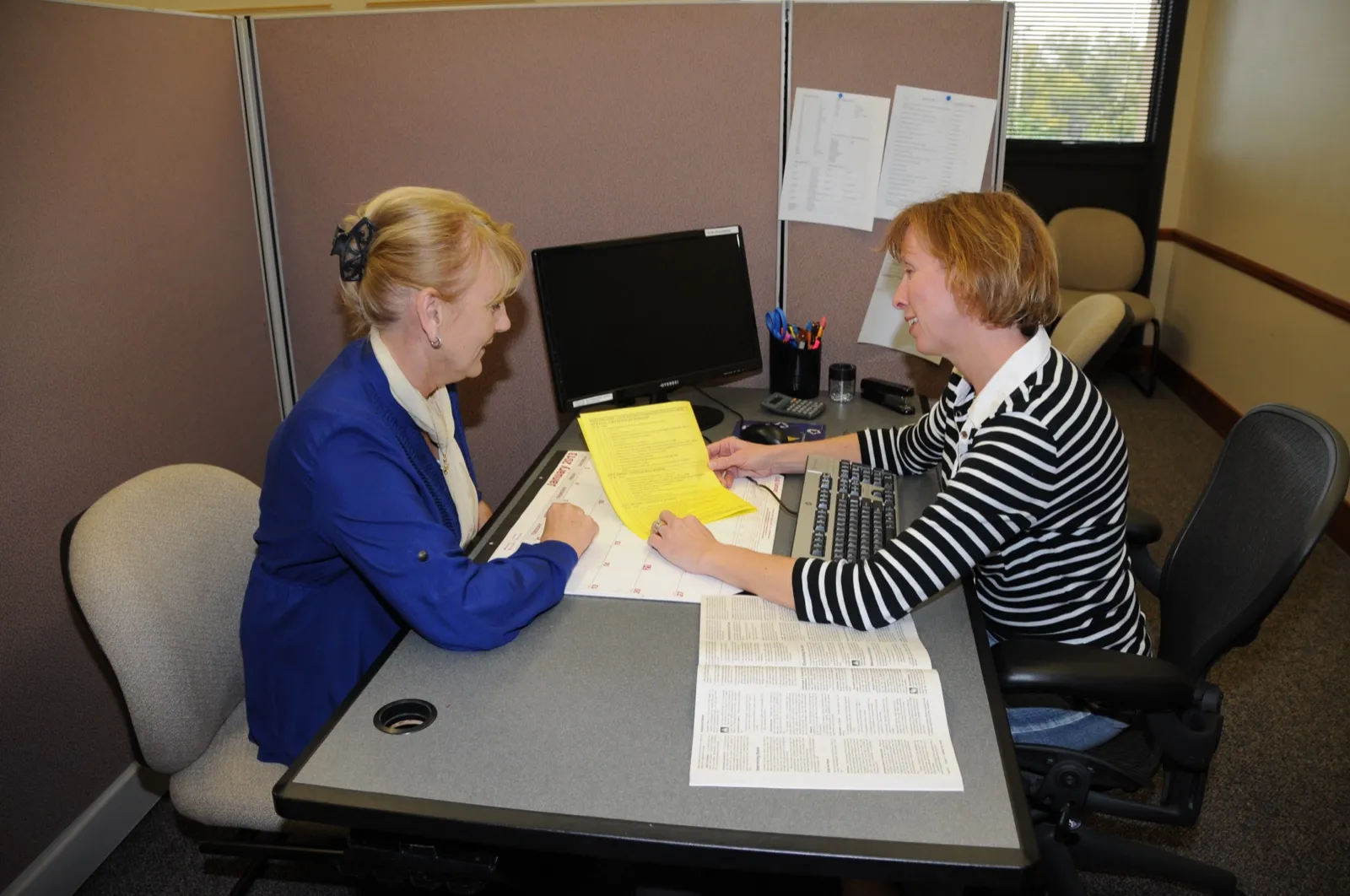 Two tax preparers at a desk going over a set of tax forms together