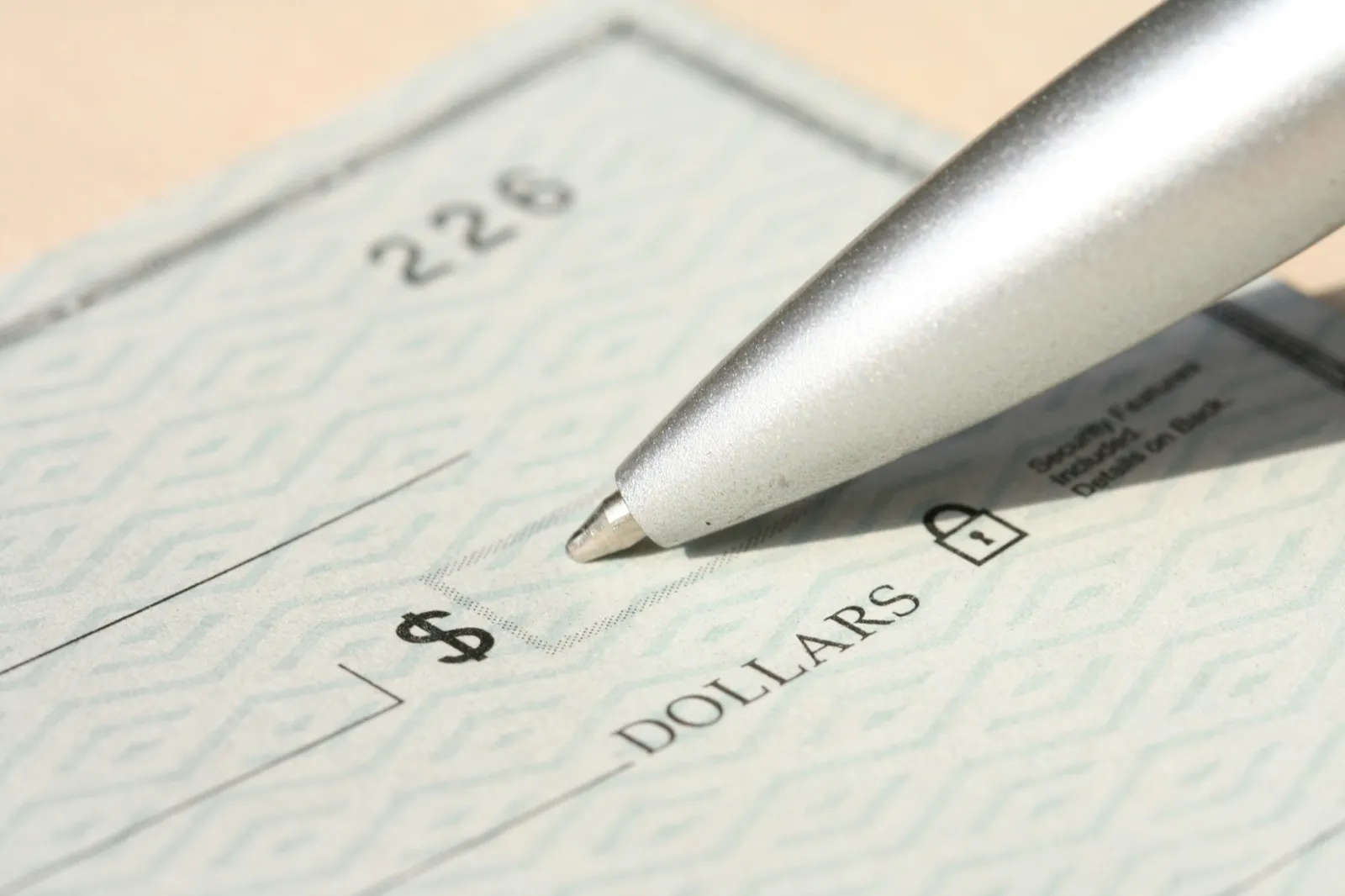 A silver pen held over the amount line of a blank paper check