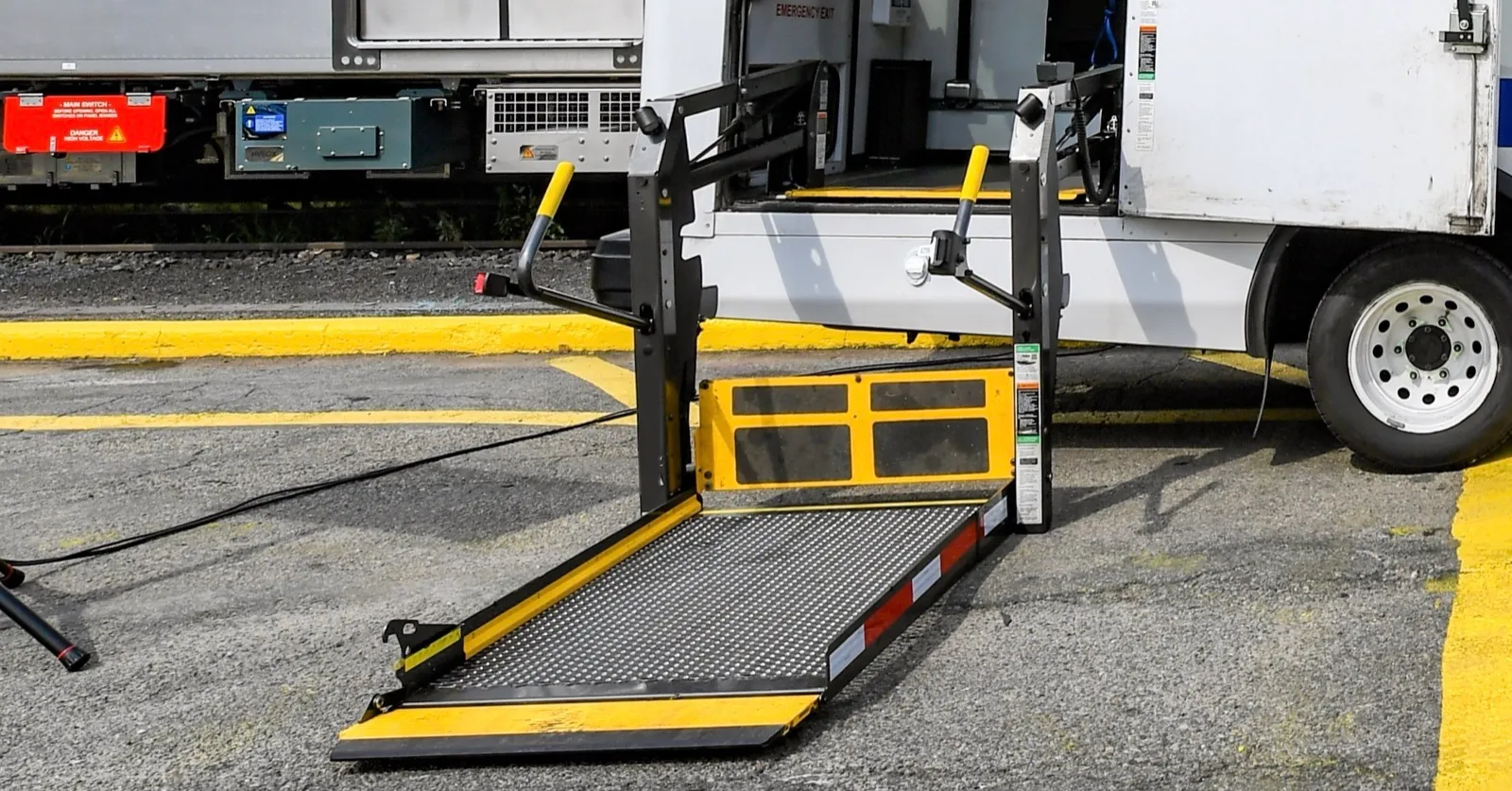 A wheelchair lift lowered to the pavement at the back of a white passenger van