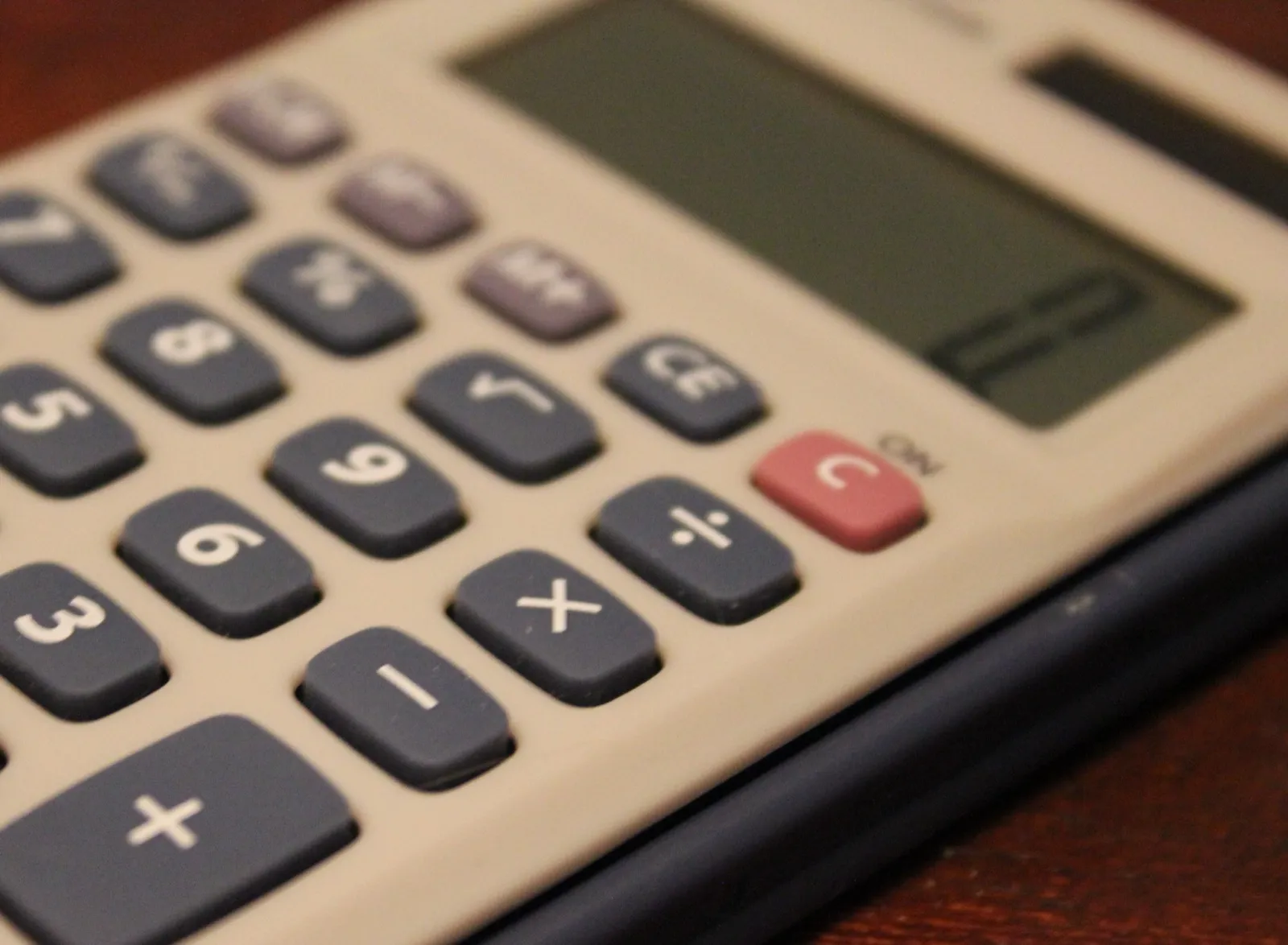 Close view of the keys of a desk calculator, including the plus, minus, and percent keys