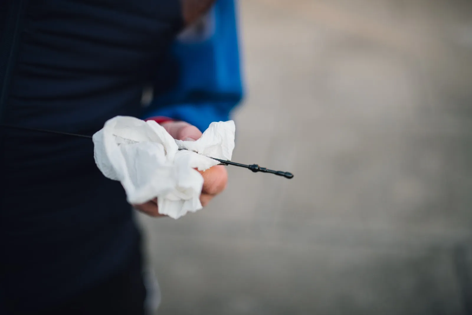 A mechanic holds an engine oil dipstick and a paper towel while checking the oil level