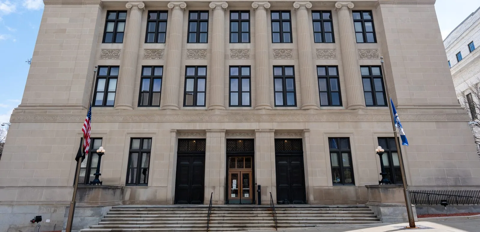 The columns, three entrance doors, and wide stone steps of the Albany County Courthouse on Eagle Street in Albany, New York