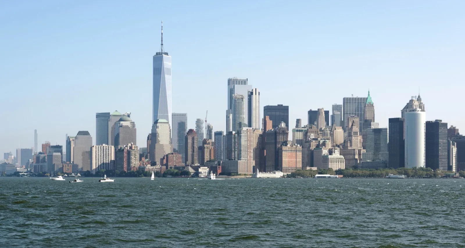 The Lower Manhattan skyline seen from Upper New York Bay on a clear day, with small boats on the water