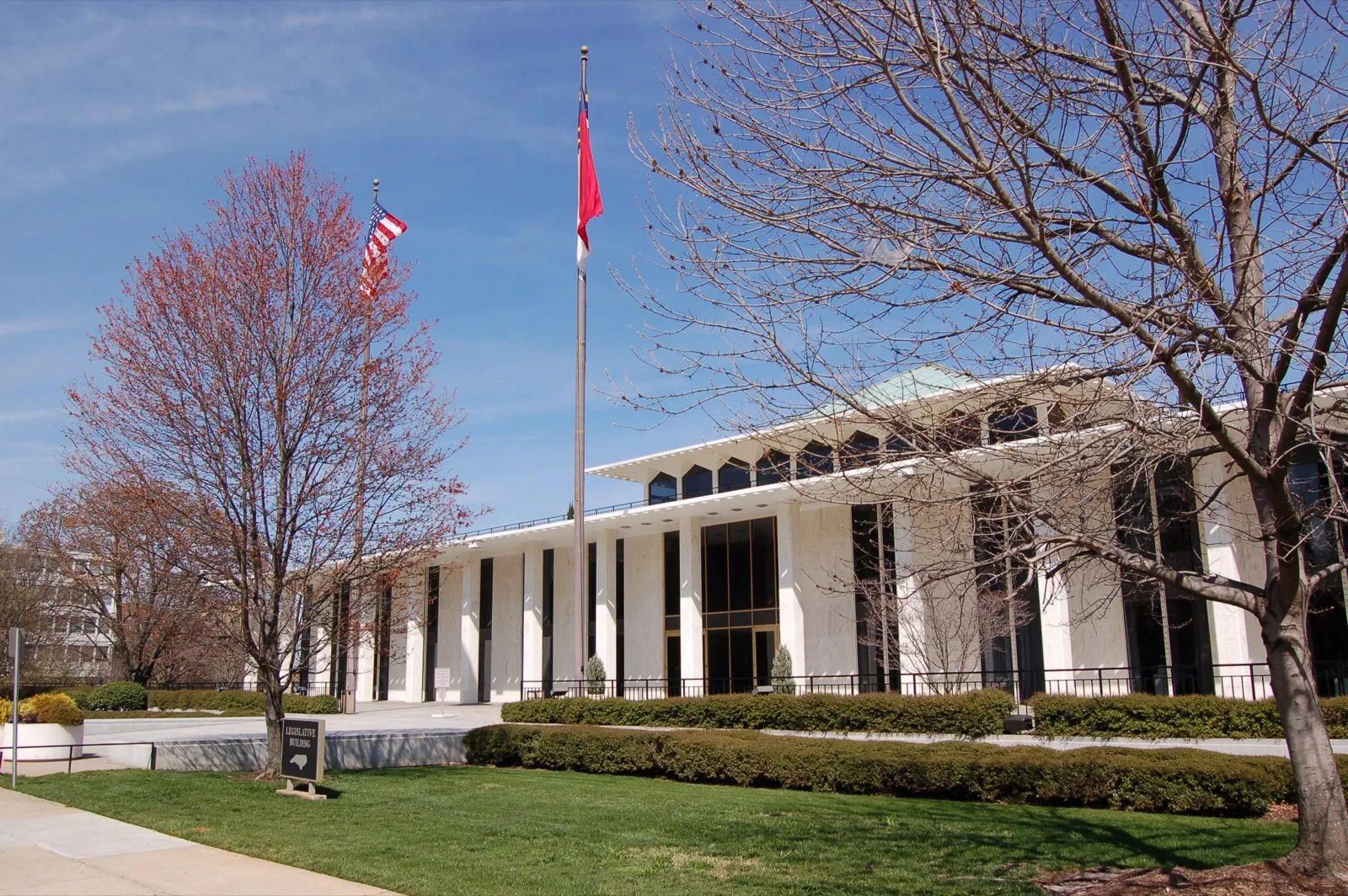 The North Carolina Legislative Building in Raleigh, with the U.S. and North Carolina flags flying out front on a spring day