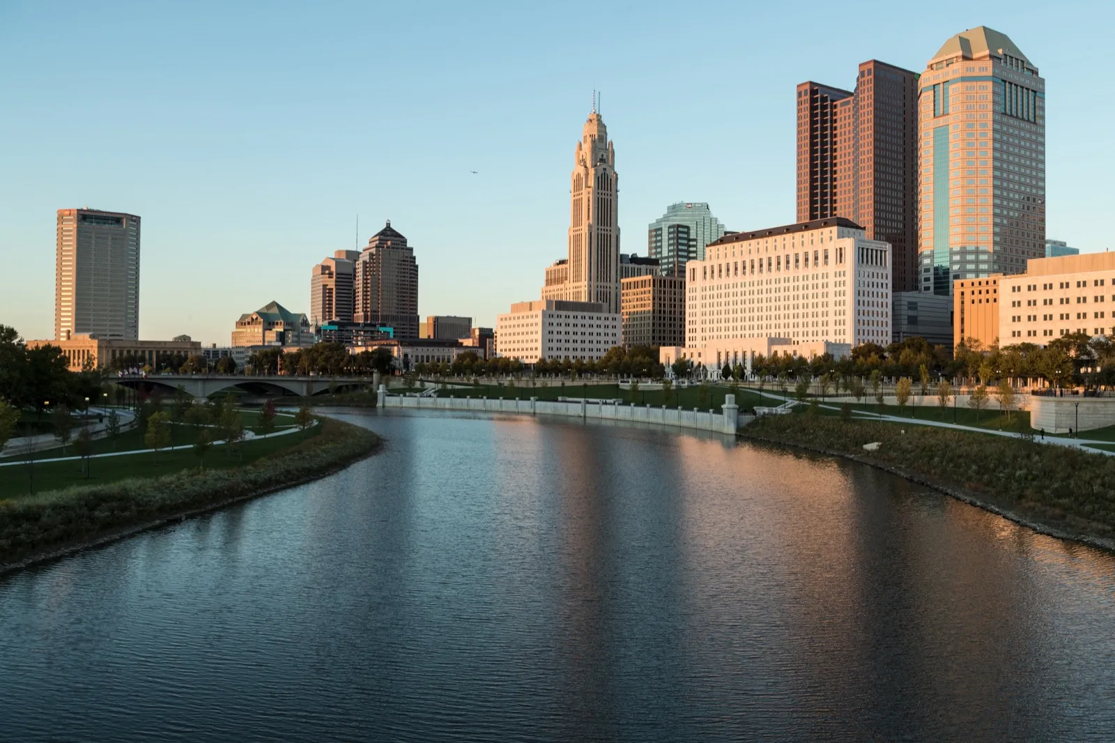 The downtown Columbus skyline at sunset, with the LeVeque Tower rising above the Scioto River and its riverfront park