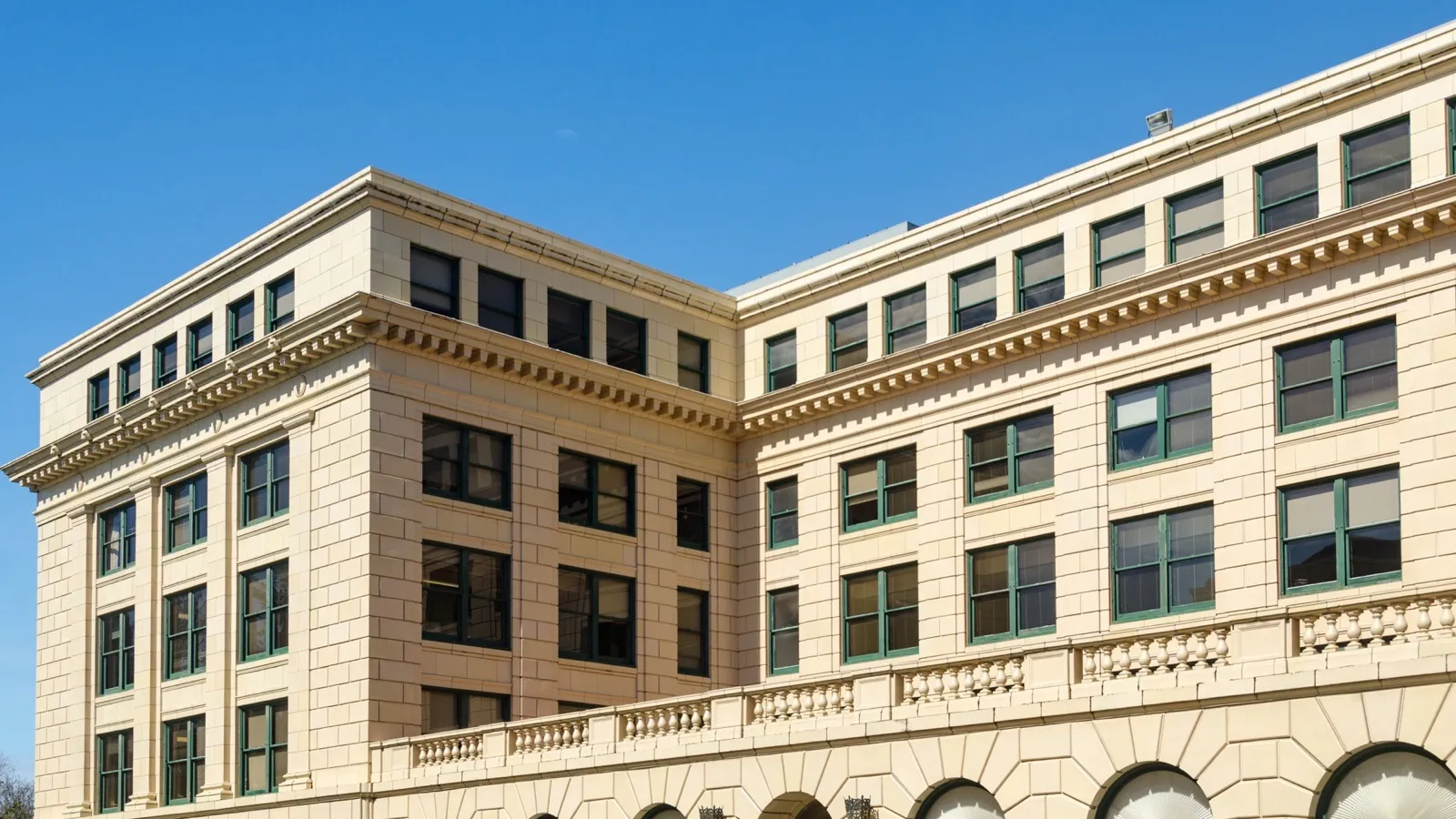 The cream upper floors and green window frames of the Justice Building, the Oregon Department of Justice offices in Salem, under a blue sky