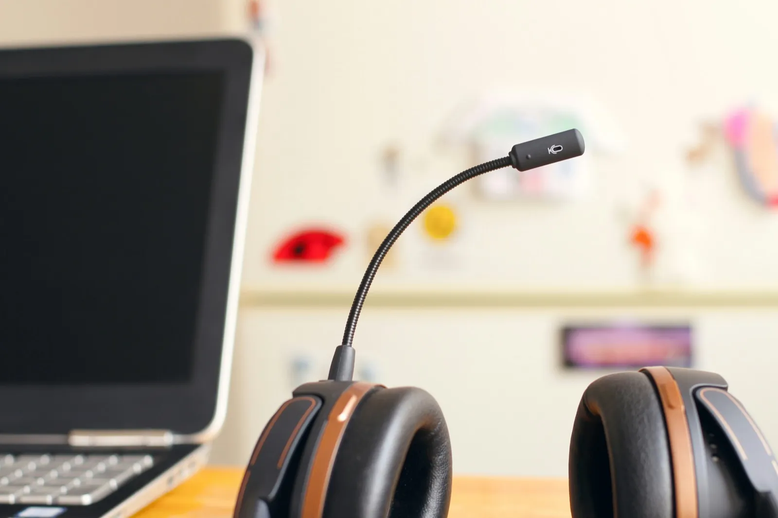 A call headset with a boom microphone resting on a desk beside an open laptop