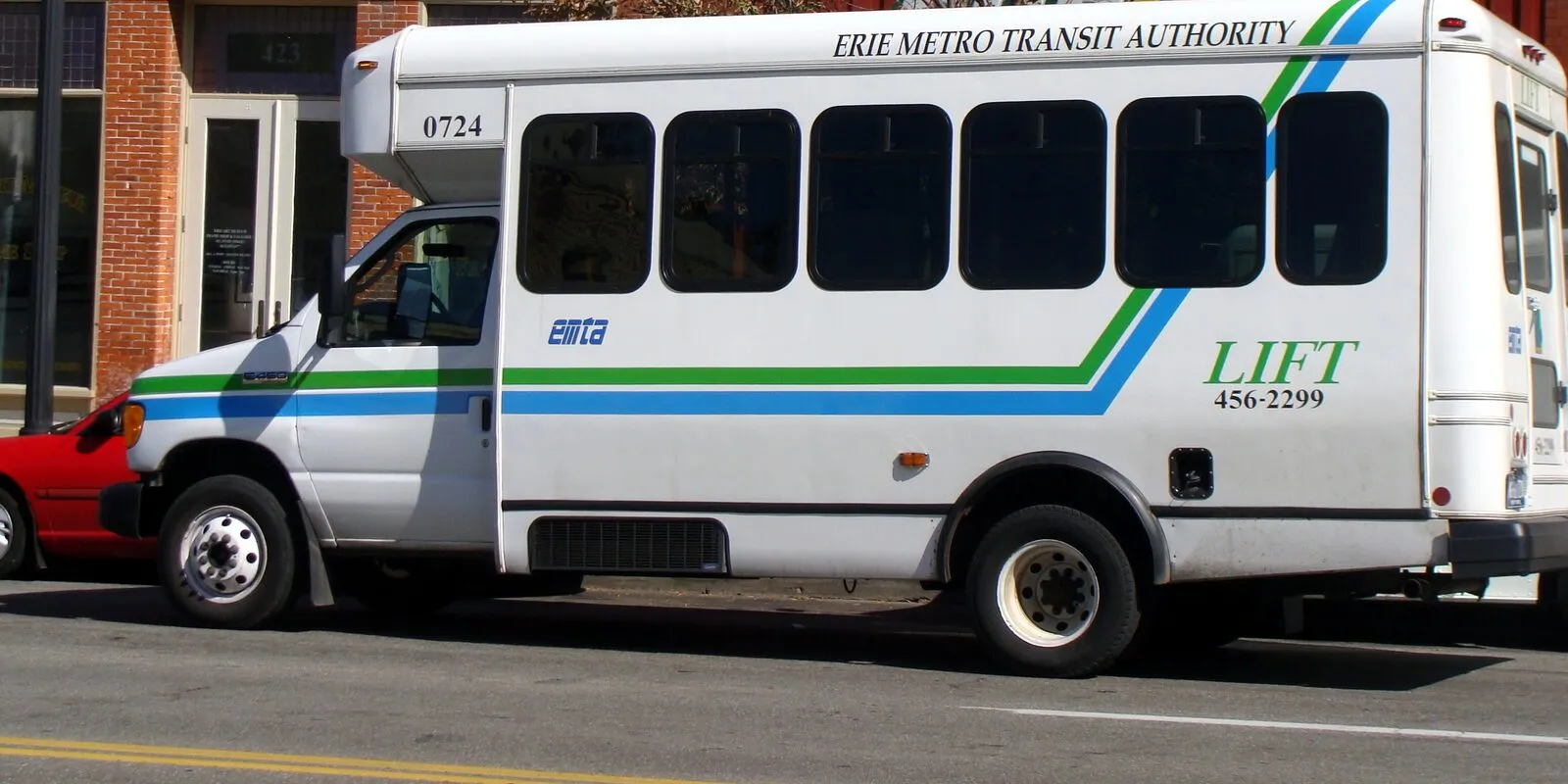 A white Erie Metro Transit Authority paratransit bus parked along a brick storefront street in Erie, Pennsylvania