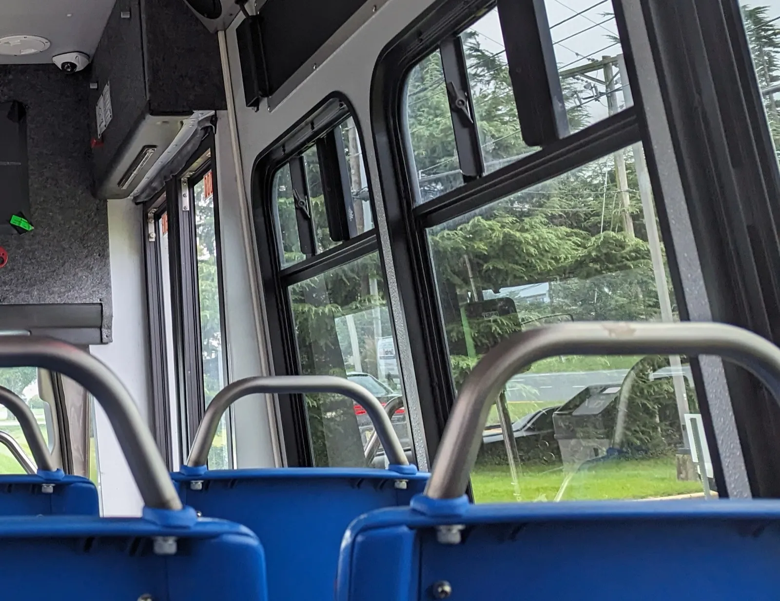 Rows of empty blue passenger seats and large side windows inside a small transit bus