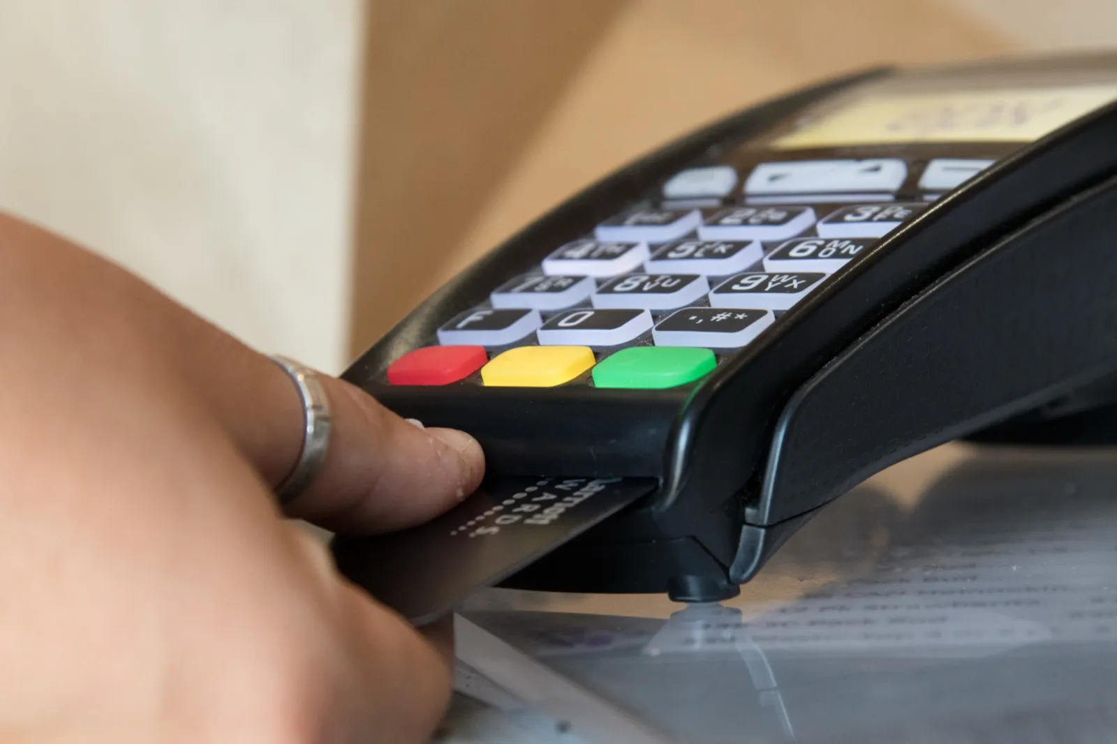A hand inserting a payment card into a card reader with a keypad