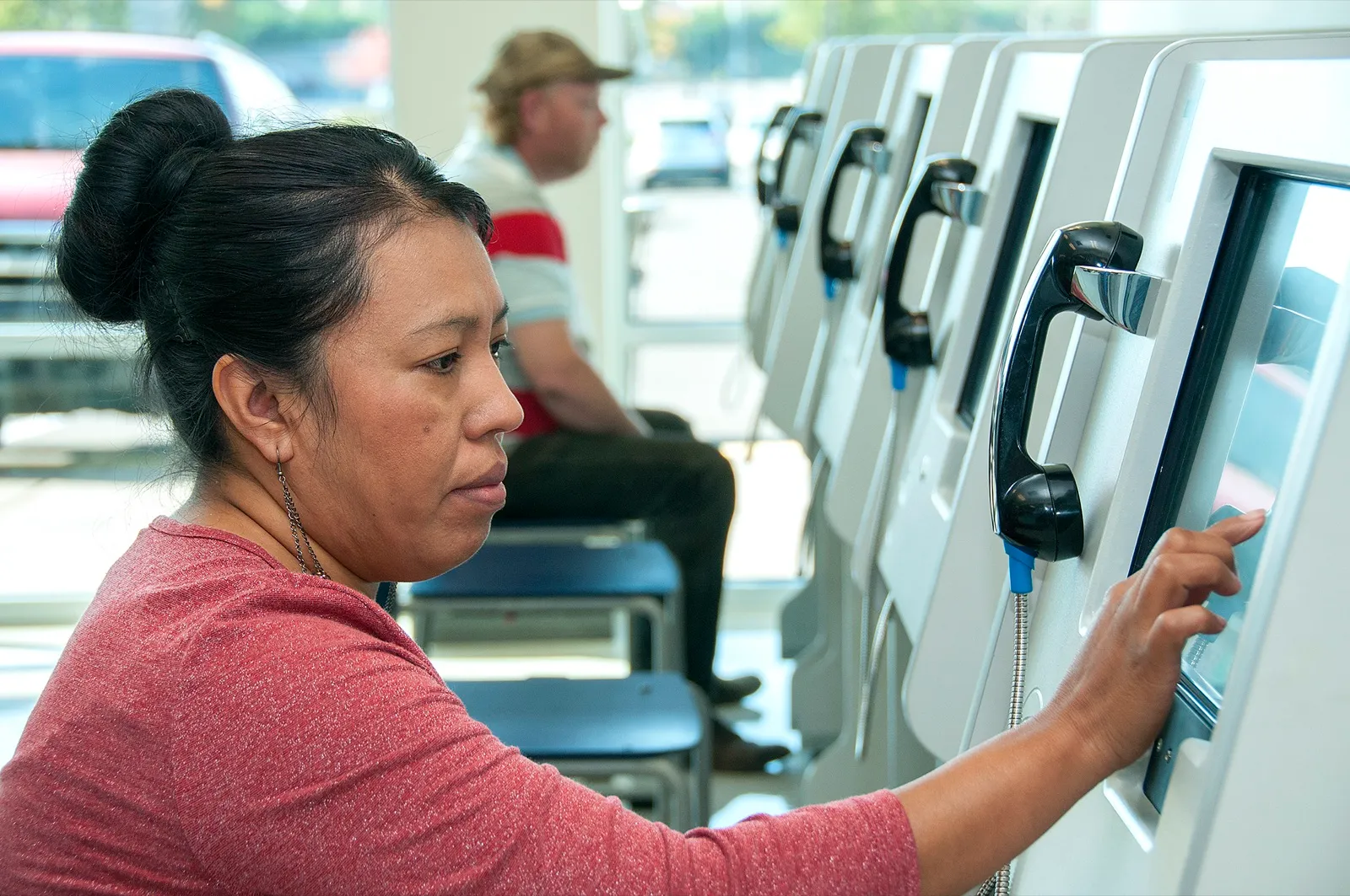 A woman at a driver licensing office touches the screen of a computer testing station while taking a knowledge test