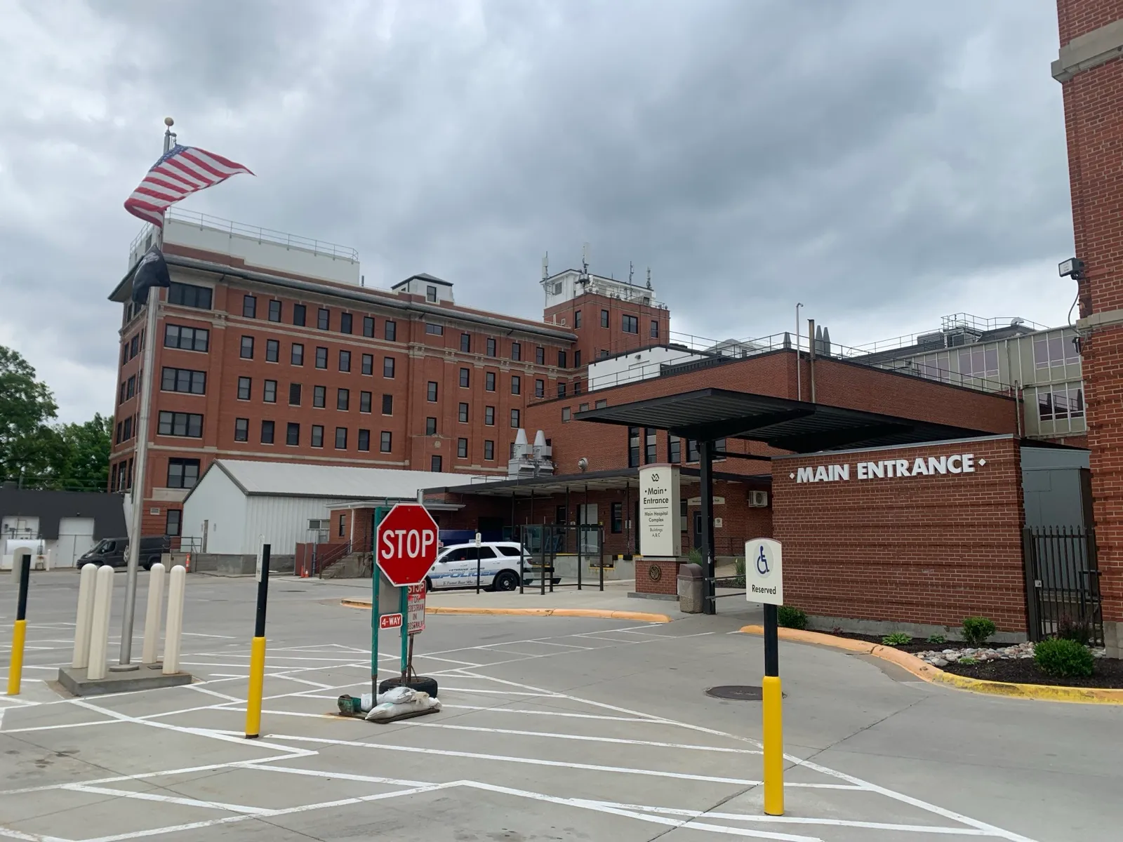 The covered main entrance and drop-off lane of a brick VA medical center, with a reserved accessible parking sign in front