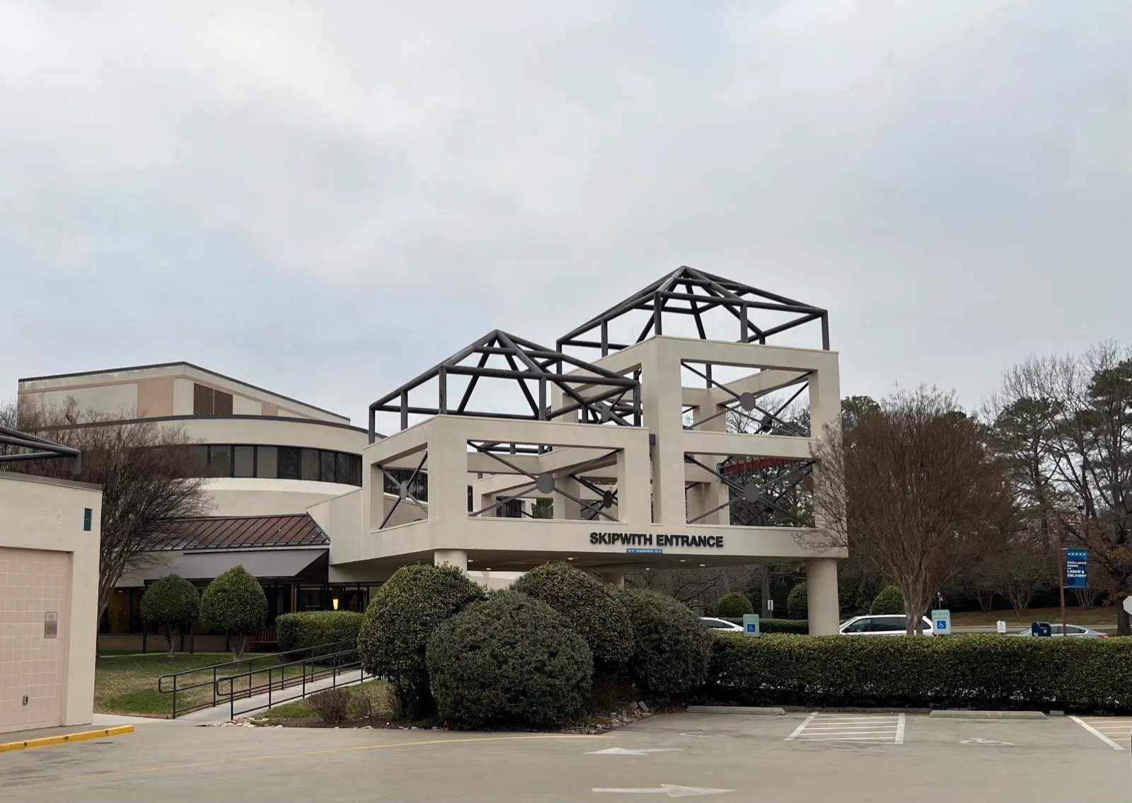 The covered Skipwith Entrance of a hospital in Henrico County, Virginia, with a drop-off drive, a ramp with handrails, and accessible parking signs